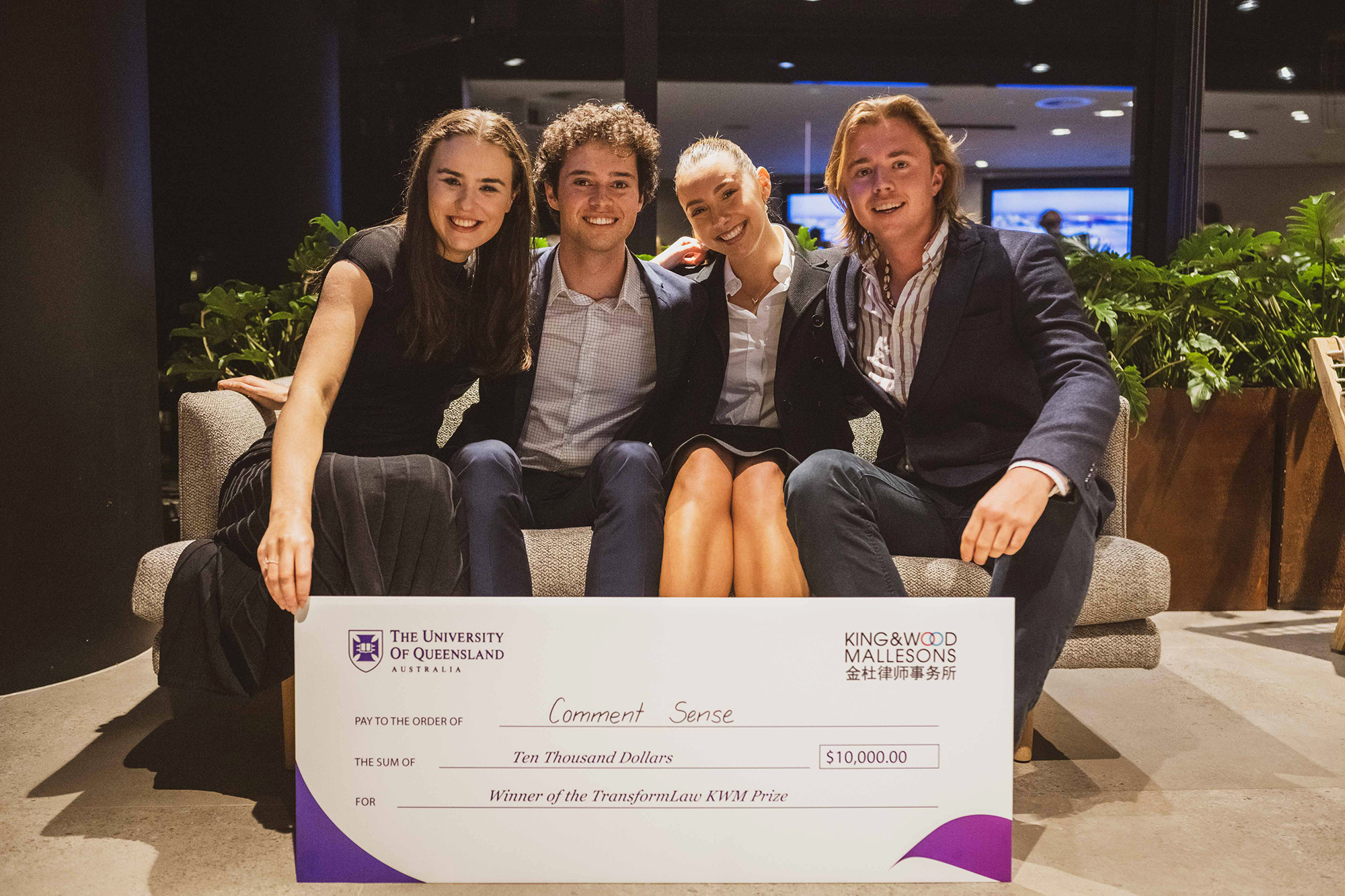 Student sitting on couch holding novelty sized cheque