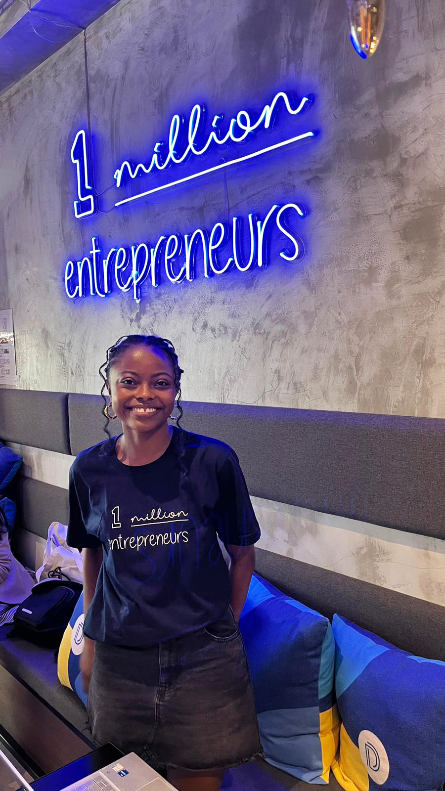 Nyenyezi Murhi standing under neon light reading '1 million entrepreneurs'