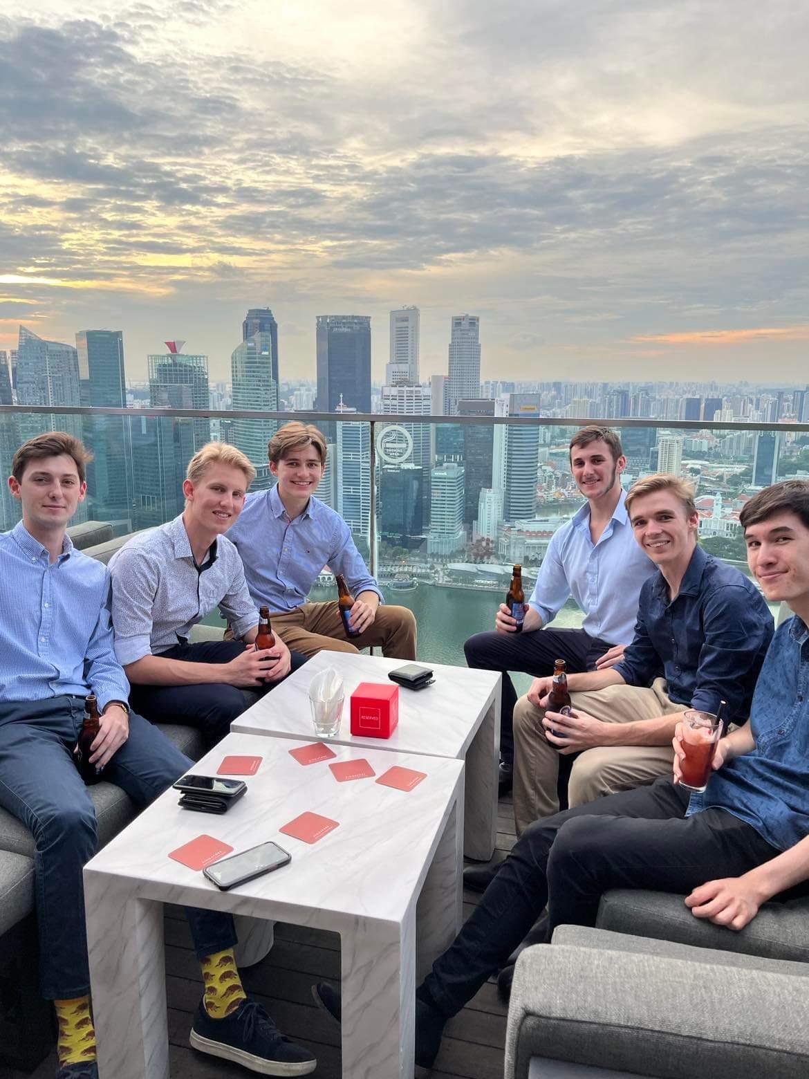 Six student sitting on rooftop in with Singapore skyline in background