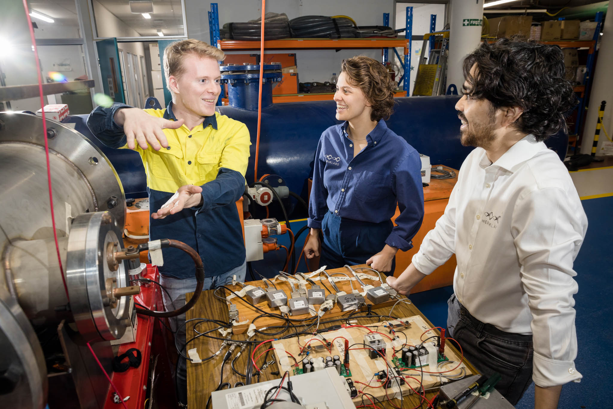 Herik Labs team talking in front on electrical equipment in UQ hypersonics lab 