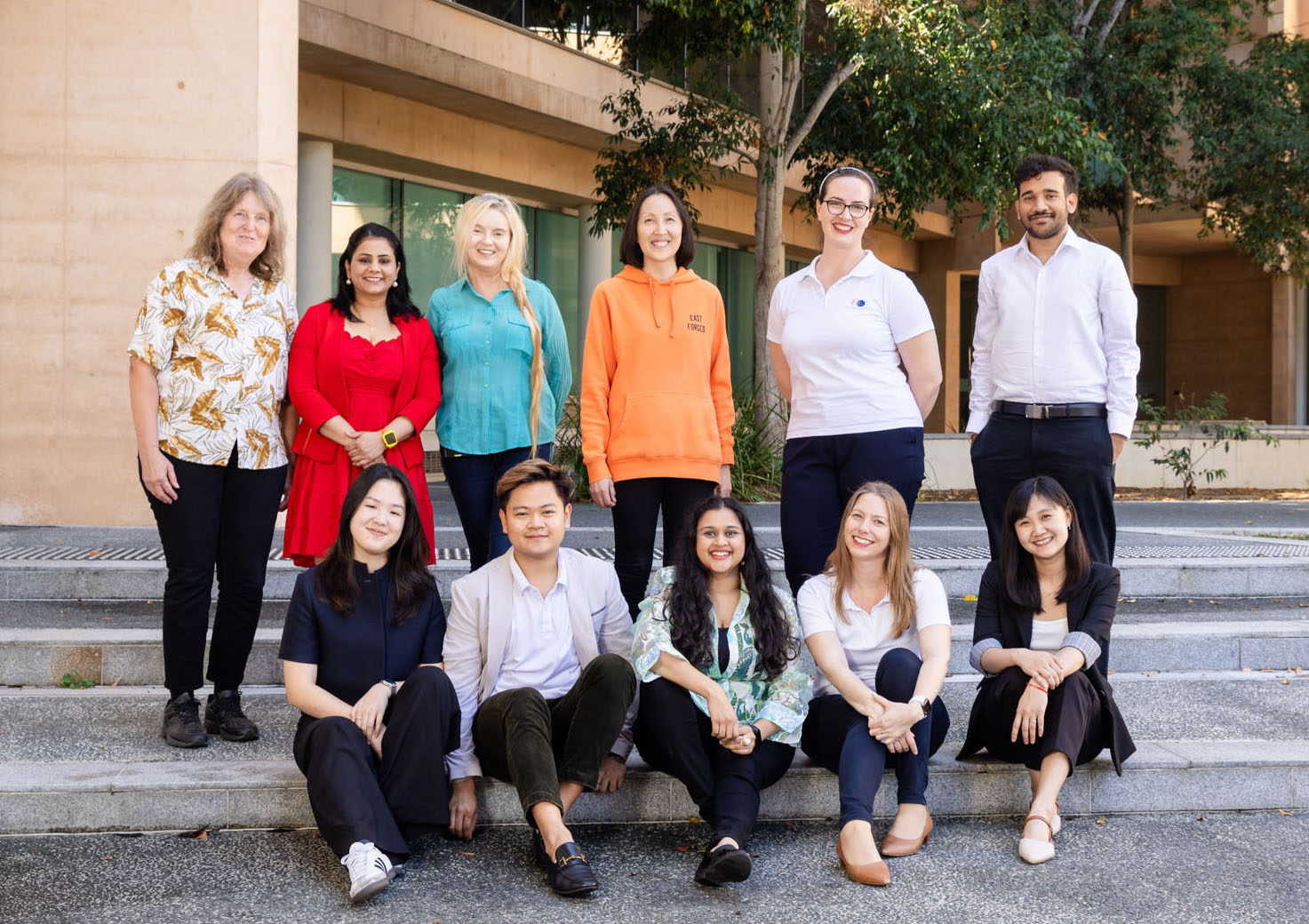 group of founders standing and sitting in two rows outside steps