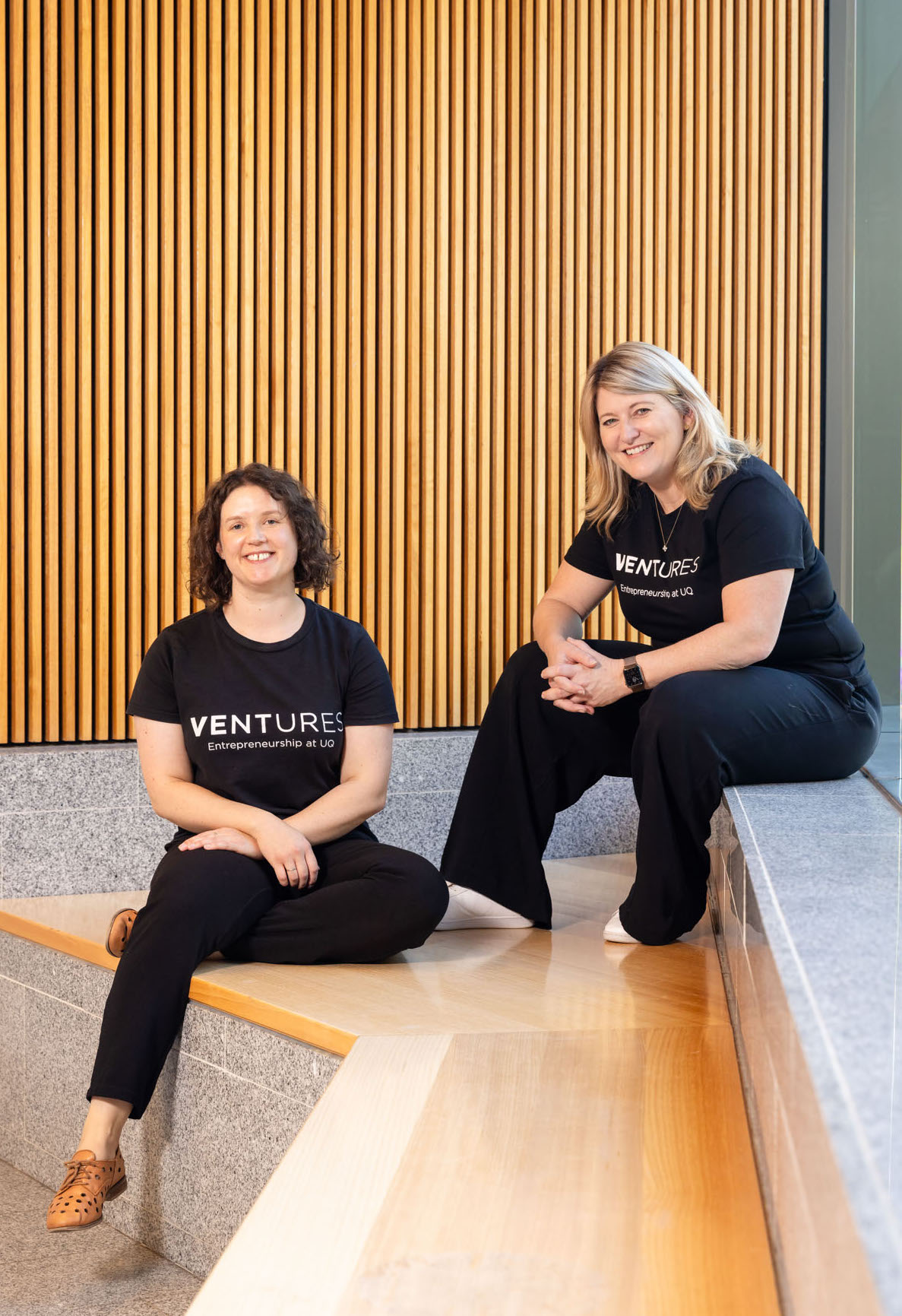 Ventures staff sitting on step with wood panelling in background