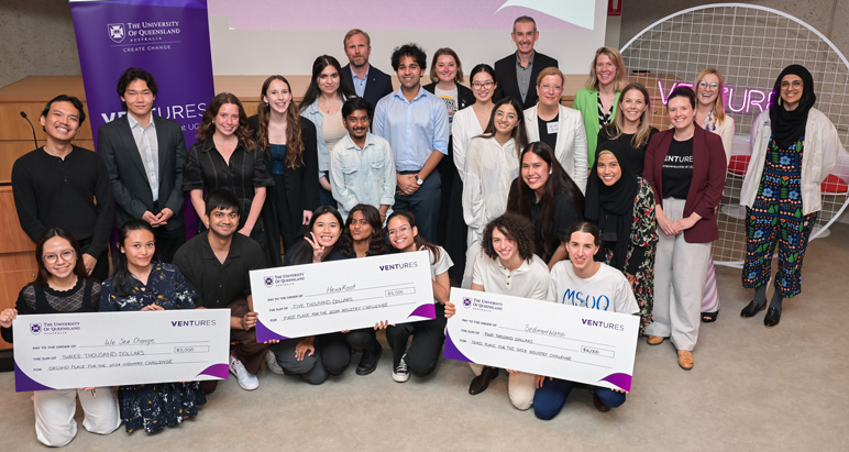 Happy young Ventures' participants - winning three teams squatting at the front holding their oversized cheques up