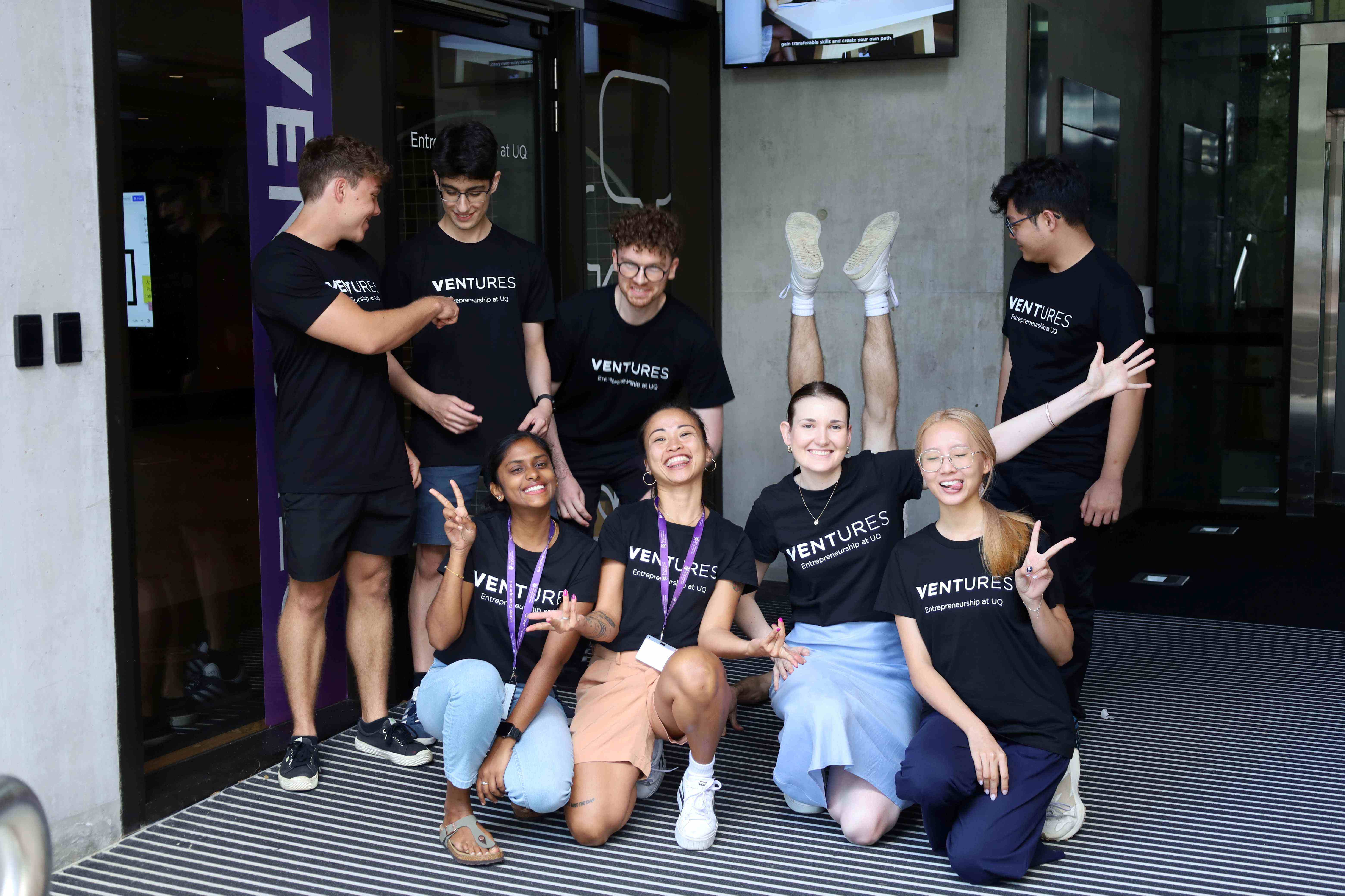 a group of young people between 20 and 25 wearing black tshirts that read VENTURES and pulling a funny pose each. The image is meant to convey the lighthearted approach to Ambassador work with Ventures.