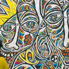 Black man walking past the Berlin Wall - with graffiti of smiling faces