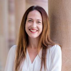 Pro-Vice-Chancellor (Global Engagement and Entrepreneurship) Dr Jessica Gallagher leaning against a sandstone column in the Great Court