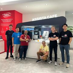 Student standing in front of robotic arm at Singapore tech startup