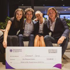 Students sitting on couch holding novelty sized cheque