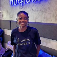 Nyenyezi Murhi standing under neon light reading '1 million entrepreneurs'