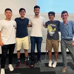 Team of five students standing at front of lecture theatre
