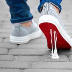 Person on street wearing sneakers stepping in chewing gum 