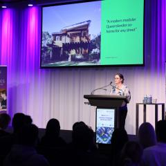 Claire Ashman pitching on stage with purple lighting in the background