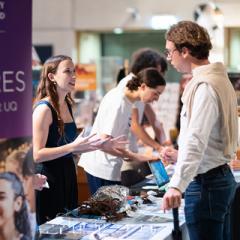 Young woman with plastics picked up from ocean speaking at Industry fair to a man asking about her project