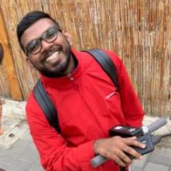 tony jojo smiling at the camera. he's wearing a red jacket