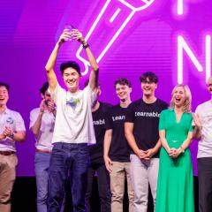 People celebrating on stage holding up trophy