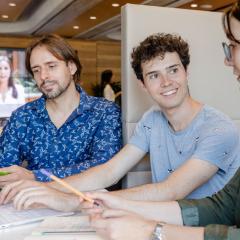 Students sitting at a table brainstorming on a laptop