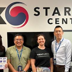 Group of women and men in front of a Korean Start Up centre logo smiling
