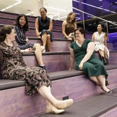UQ female Ventures staff members sitting and talking on purple stairs