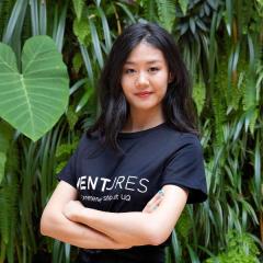 Rachel Huang in front of green wall (leafy plants) - she's wearing the Ventures entrepreneurship at UQ tshirt