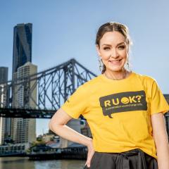 Aislinn Sharp wearing 'R U OK?' yellow tshirt in front of Brisbane skyline