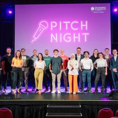 ilab cohort standing on stage at the Tivoli with 'Pitch Night' text on purple screen in the background
